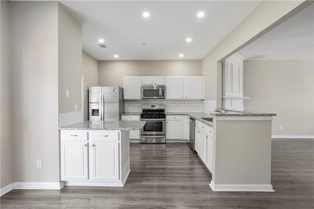 kitchen with decorative backsplash, dark hardwood / wood-style flooring, appliances with stainless steel finishes, white cabinetry, and light stone counters