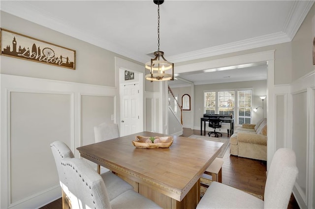 dining area featuring a decorative wall, stairway, crown molding, and dark wood-type flooring