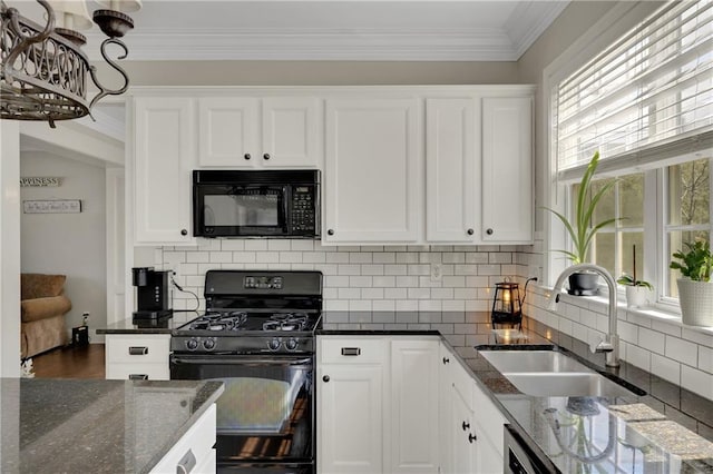 kitchen featuring dark stone counters, a sink, black appliances, white cabinetry, and crown molding