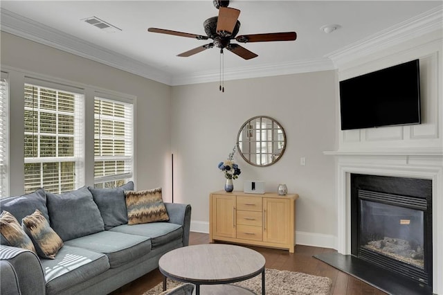 living room featuring baseboards, visible vents, dark wood finished floors, a glass covered fireplace, and crown molding