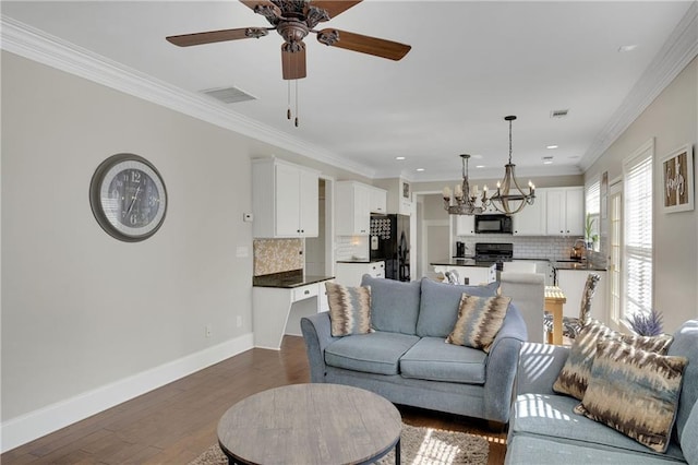 living area with visible vents, crown molding, dark wood-type flooring, and baseboards