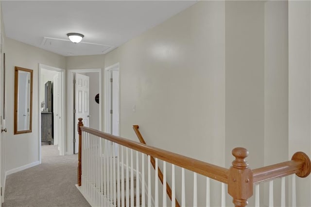 corridor with an upstairs landing, attic access, baseboards, and carpet floors