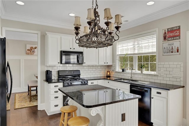 kitchen with a sink, black appliances, white cabinets, and ornamental molding