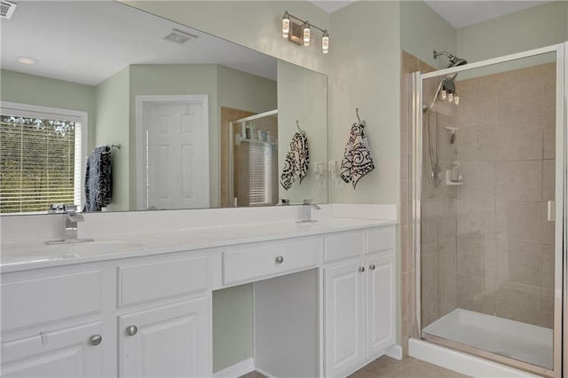 bathroom featuring double vanity, visible vents, a shower stall, and a sink