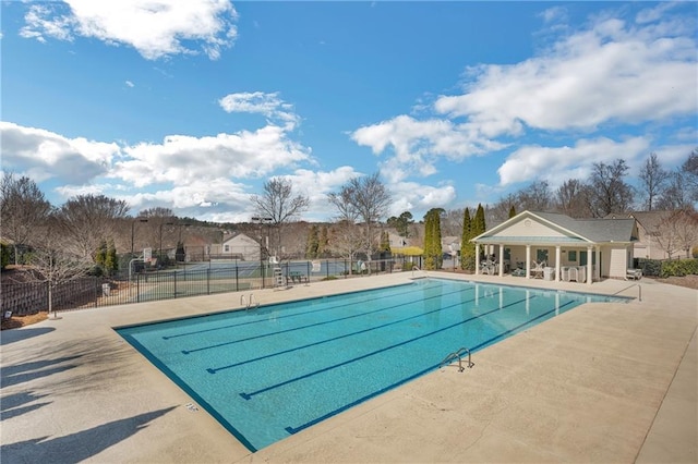 community pool with a patio area and fence