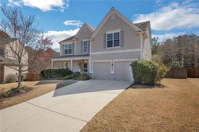 traditional home with a front lawn, fence, concrete driveway, covered porch, and a garage