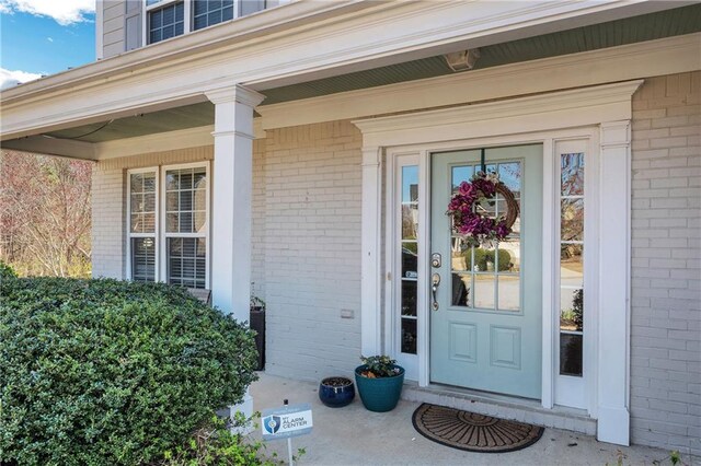 property entrance with brick siding and a porch