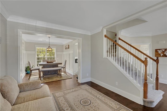 living room with crown molding, dark wood-type flooring, stairway, wainscoting, and a decorative wall