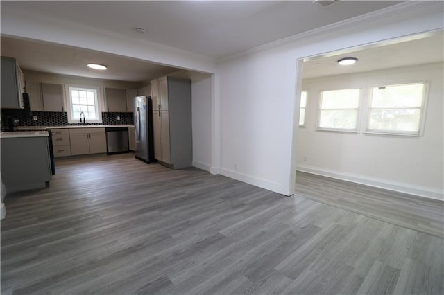 kitchen featuring sink, stainless steel appliances, backsplash, wood-type flooring, and gray cabinets