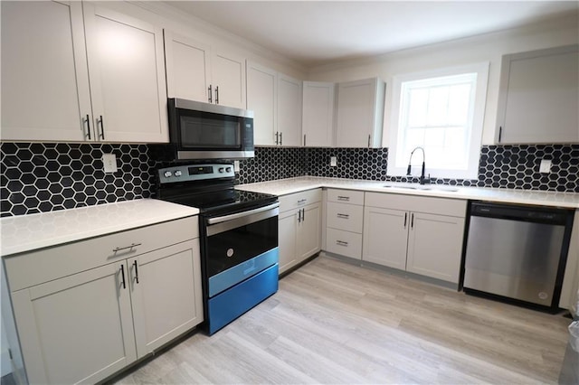 kitchen featuring appliances with stainless steel finishes, backsplash, sink, light hardwood / wood-style flooring, and gray cabinets