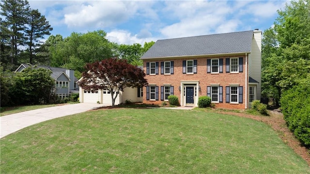 colonial inspired home with a chimney, a front yard, a garage, brick siding, and concrete driveway