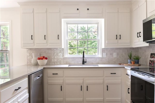kitchen featuring light countertops, appliances with stainless steel finishes, decorative backsplash, and a sink