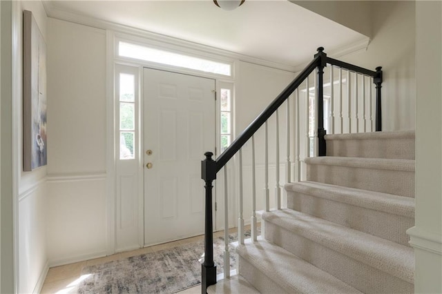 entryway with tile patterned flooring, ornamental molding, and stairs