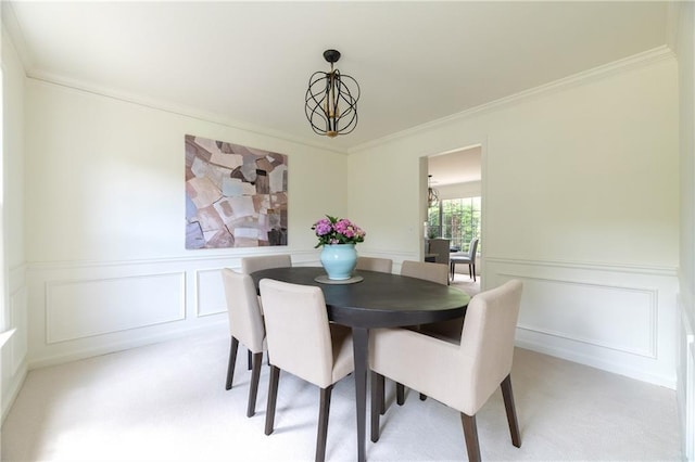 dining area with wainscoting, ornamental molding, light carpet, and a decorative wall