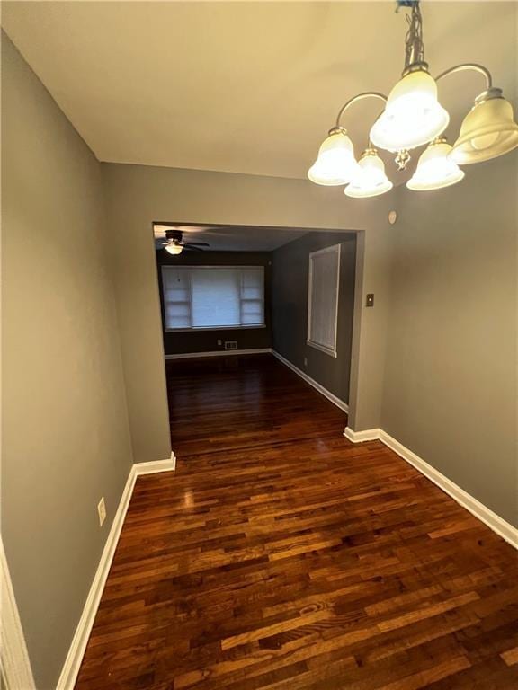 hallway featuring dark wood-type flooring and a chandelier