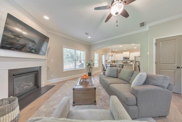 4230 Old Cherokee St, Acworth, GA 30101 - living area with crown molding, a chandelier, light wood finished floors, a glass covered fireplace, and a ceiling fan