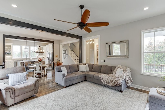 living room with hardwood / wood-style floors, plenty of natural light, and ceiling fan with notable chandelier