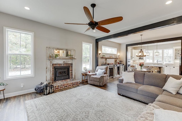 living room with beam ceiling, wood-type flooring, and ceiling fan with notable chandelier