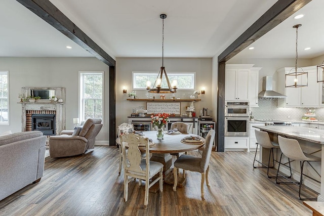 dining area with a fireplace, hardwood / wood-style flooring, and beam ceiling