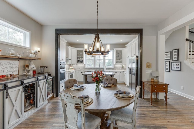 dining space featuring hardwood / wood-style floors, wine cooler, and an inviting chandelier