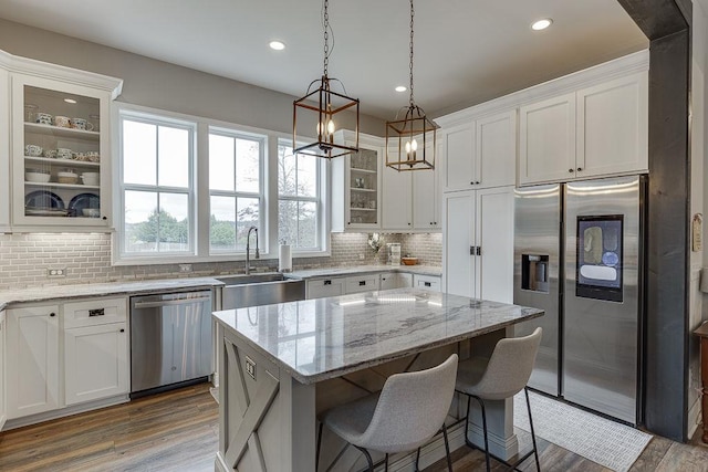 kitchen with stainless steel appliances, white cabinetry, sink, and a kitchen island