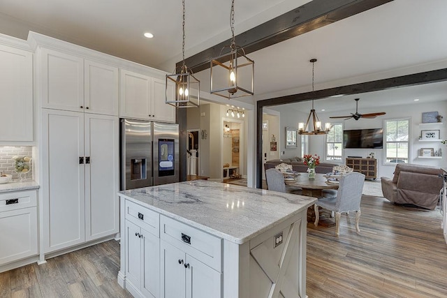 kitchen with beamed ceiling, tasteful backsplash, decorative light fixtures, white cabinets, and stainless steel fridge with ice dispenser