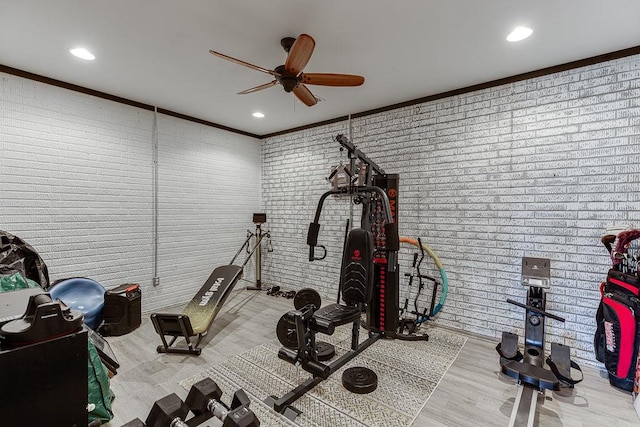 exercise room featuring light hardwood / wood-style flooring, brick wall, and crown molding