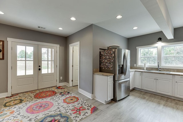 kitchen featuring white cabinetry, sink, stainless steel refrigerator with ice dispenser, light wood-type flooring, and french doors