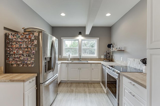 kitchen featuring beamed ceiling, sink, appliances with stainless steel finishes, white cabinets, and light wood-type flooring