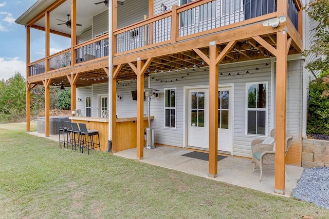 rear view of property with a wooden deck, ceiling fan, a patio, and a yard