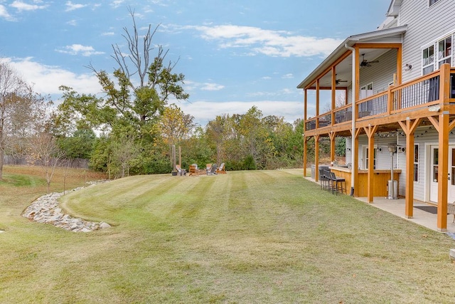 view of yard featuring a wooden deck, ceiling fan, and a patio