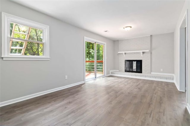 unfurnished living room with a fireplace, a healthy amount of sunlight, and hardwood / wood-style floors