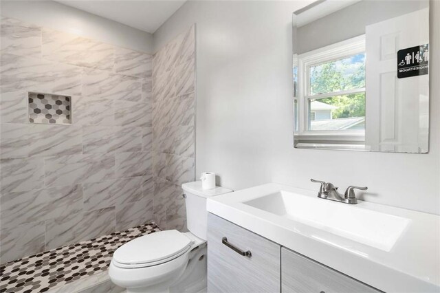 bathroom featuring vanity, toilet, and tiled shower