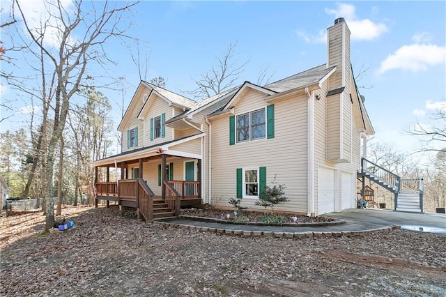 view of front of home featuring driveway, a porch, stairway, a garage, and a chimney