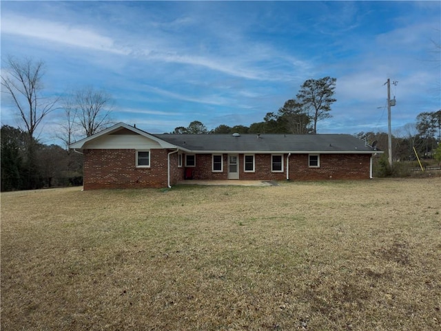 back of property with brick siding, a lawn, and a patio