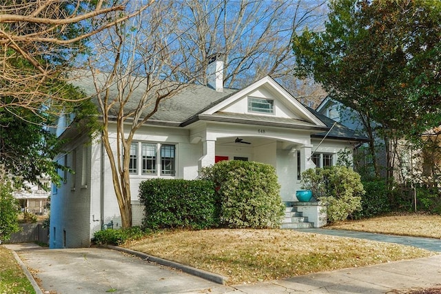 view of front of home featuring ceiling fan, brick siding, and a chimney