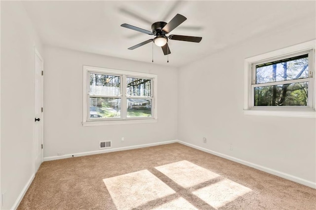 carpeted spare room featuring ceiling fan and plenty of natural light