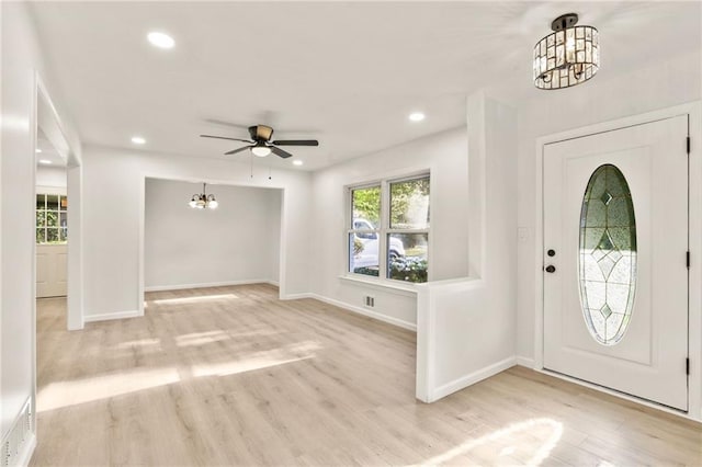 foyer entrance with light wood-type flooring and ceiling fan with notable chandelier