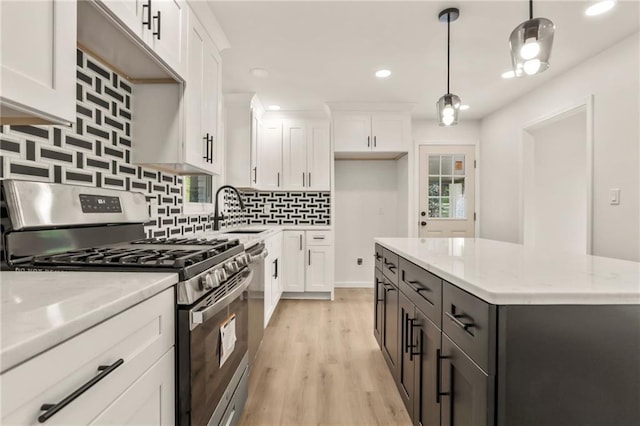 kitchen featuring decorative light fixtures, stainless steel range with gas cooktop, and white cabinetry