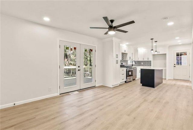 interior space featuring hanging light fixtures, french doors, white cabinets, stainless steel range oven, and a center island