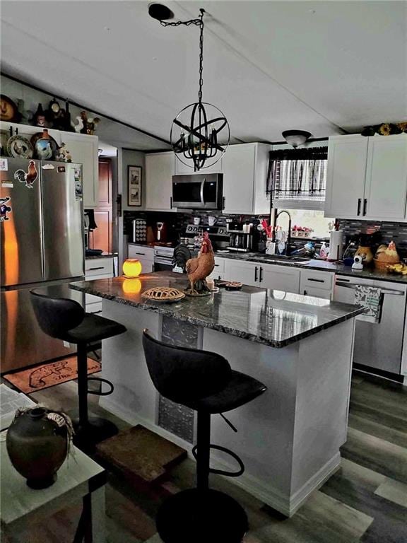 kitchen featuring sink, appliances with stainless steel finishes, white cabinetry, hanging light fixtures, and a center island