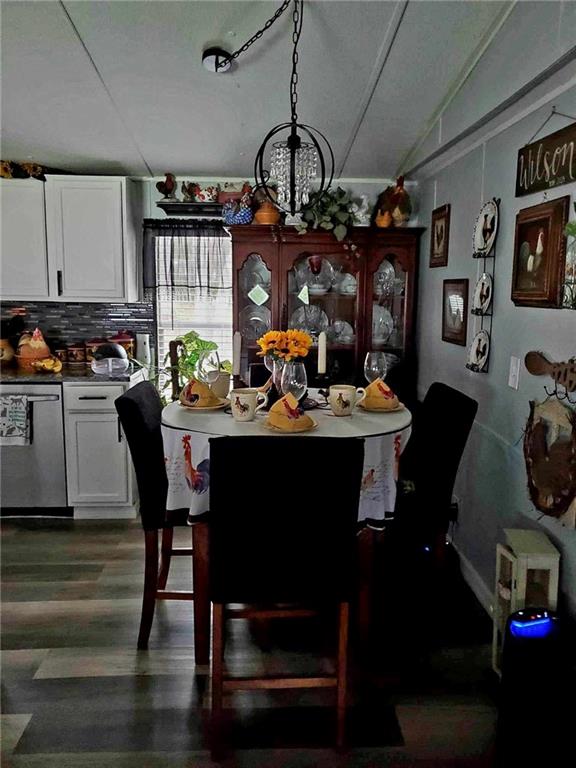 dining area featuring vaulted ceiling, a notable chandelier, and dark hardwood / wood-style flooring