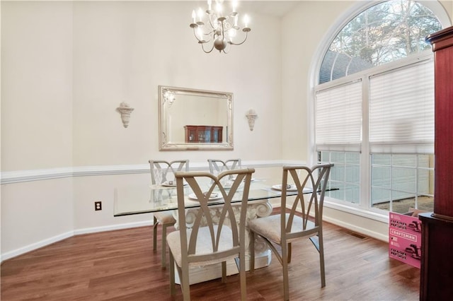 dining space with dark hardwood / wood-style flooring and an inviting chandelier