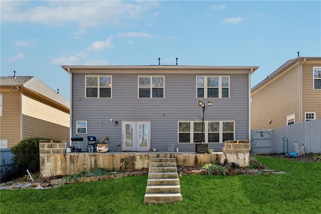 back of house featuring stairs, french doors, fence, and a lawn