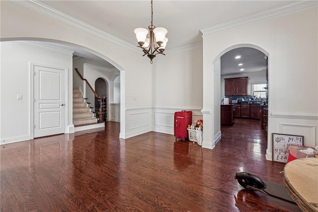 dining area with dark wood-style floors, stairs, ornamental molding, and a decorative wall