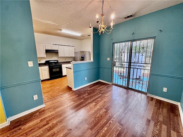 kitchen featuring stainless steel refrigerator with ice dispenser, wood-type flooring, black range, a chandelier, and white cabinetry