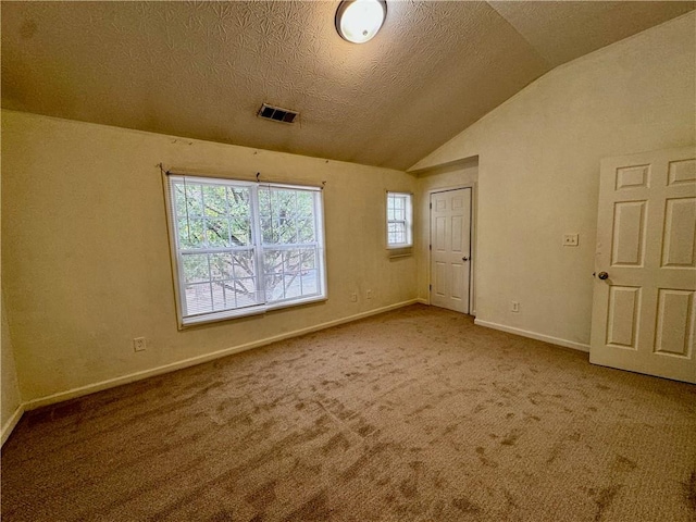 spare room featuring carpet flooring, a textured ceiling, and vaulted ceiling