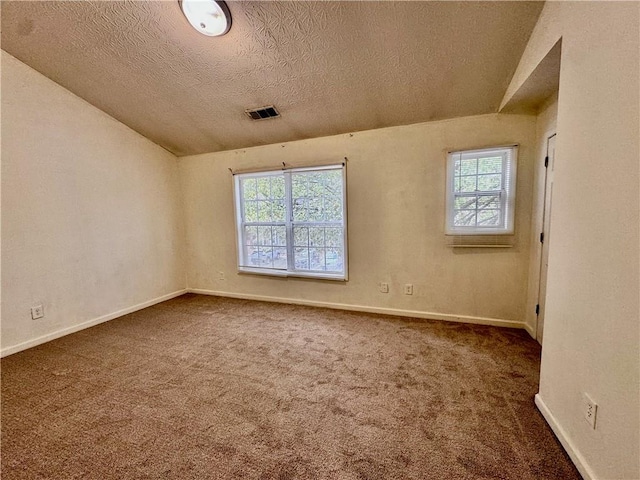 unfurnished room with vaulted ceiling, dark carpet, and a textured ceiling