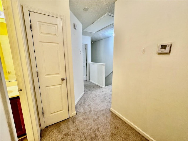 corridor with a textured ceiling and light carpet