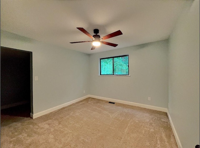 empty room with ceiling fan and light carpet